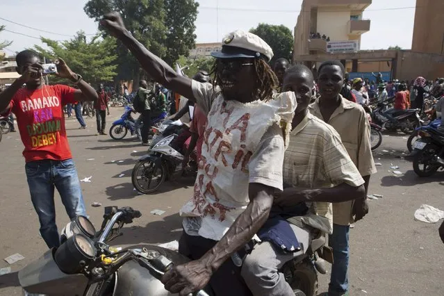 People celebrate the departure of Burkina Faso's President Blaise Compaore in Ouagadougou, capital of Burkina Faso, October 31, 2014. General Honore Traore, the head of Burkina Faso's armed forces, took power on Friday after Compaore resigned amid mass demonstrations against an attempt to extend his 27-year rule in the West African country. (Photo by Joe Penney/Reuters)