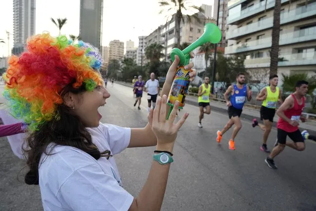 A girl uses an air horn as runners compete in the 42-kilometer (26-mile) Beirut International Marathon in Beirut, Lebanon, Sunday, November 13, 2022. (Photo by Bilal Hussein/AP Photo)