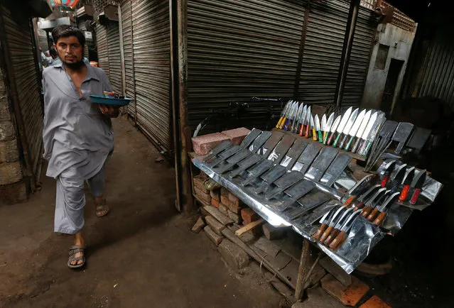 A man walks past a stall displaying knifes used for animal sacrifice ahead of the Eid al-Adha festival at a market in Karachi, Pakistan, September 12, 2016. (Photo by Akhtar Soomro/Reuters)