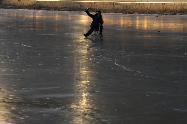 A resident takes a selfie as he skates on a frozen canal near sunset in Beijing, Wednesday, December 28, 2022. (Photo by Ng Han Guan/AP Photo)