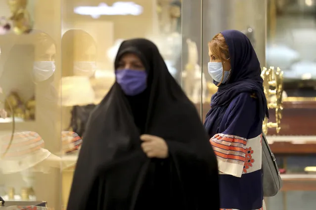 Women wearing protective face masks to help prevent spread of the coronavirus walk through a shopping center, in Tehran, Iran, Wednesday, August 19, 2020. Iran surpassed 20,000 confirmed deaths from the coronavirus on Wednesday, the health ministry said — the highest death toll for any Middle East country so far in the pandemic. (Photo by Ebrahim Noroozi/AP Photo)