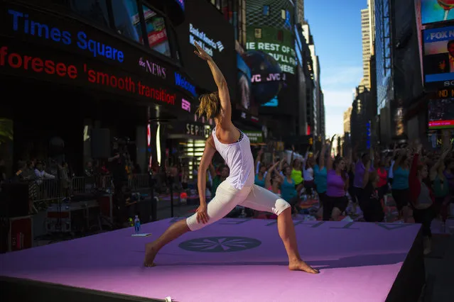 People practice yoga in Times Square as part of a Summer Solstice celebration in New York on June 21, 2014. (Photo by Eric Thayer/Reuters)