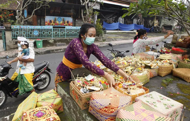 A woman gives an offering as she wears a face mask as a precaution against the new coronavirus outbreak during a Hindu ritual prayer at a temple in Bali, Indonesia, Wednesday, September 16, 2020. (Photo by Firdia Lisnawati/AP Photo)