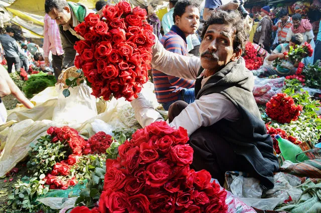 Indian flower vendors arrange roses as they wait for customers at a wholesale flower market in Kolkata on February 7, 2018. The roses are high in demand as seven days of festivity of the Valentine Week starts from February 7 with Rose Day. (Photo by Dibyangshu Sarkar/AFP Photo)