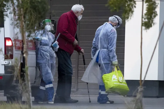 Medical workers wearing protective gear helps a man, suspected of having coronavirus out of an ambulance at a hospital in Kommunarka, outside Moscow, Russia, Tuesday, September 29, 2020. Moscow authorities are extending school holidays by a week amid a surge of new coronavirus cases. Health officials on Tuesday reported  over 8,000 new virus cases, with  over 2,000 in Moscow, the highest daily number in the Russian capital since late May. (Photo by Pavel Golovkin/AP Photo)