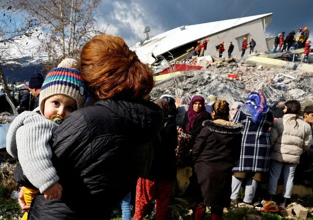 A woman holds a child as she stands near rubble and damages following an earthquake in Gaziantep, Turkey on February 7, 2023. (Photo by Suhaib Salem/Reuters)