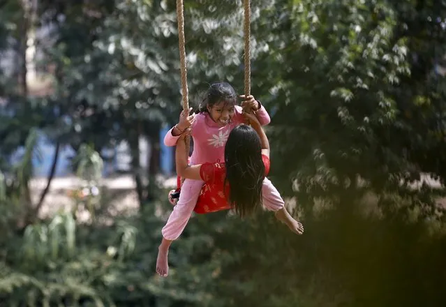 Girls play on a traditional swing during Dashain, the biggest religious festival for Hindus in Nepal, in Kathmandu, October 15, 2015. Hindus in Nepal celebrate victory over evil during the festival by flying kites, feasting, playing on swings, sacrificing animals and worshipping the Goddess Durga as well as other gods and goddesses as part of celebrations held throughout the country. (Photo by Navesh Chitrakar/Reuters)