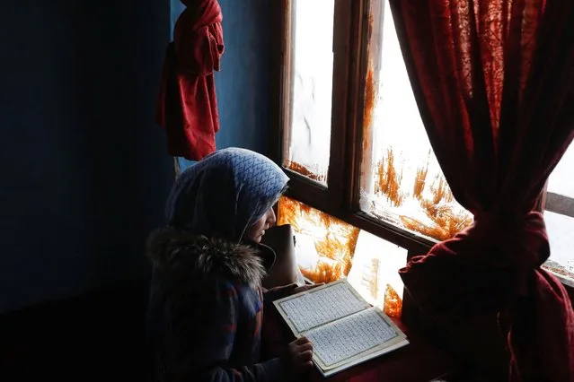 Sister of Amrullah, a child who died due to cold, reads Koran in her house in Kabul, Afghanistan on January 30, 2023. (Photo by Ali Khara/Reuters)