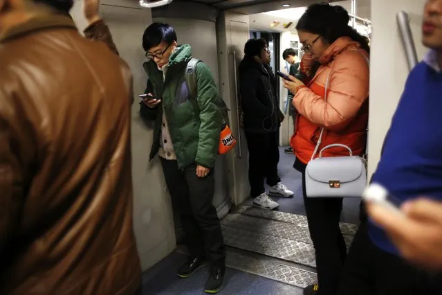 Vin Huang looks at her mobile phone as she travel on the subway on the way to her boxing training class in Shanghai December 8, 2014. (Photo by Carlos Barria/Reuters)