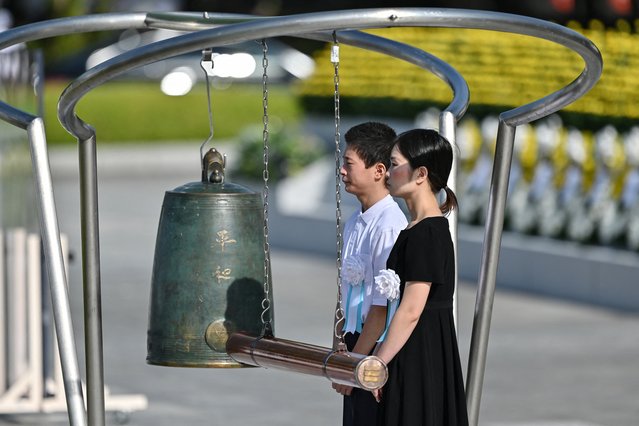 A young man and woman prepare to ring the bell to remember those lost in the bombing, during the Peace Memorial Ceremony to mark the 80th anniversary of the world's first atomic bomb attack, in the city of Hiroshima on August 6, 2025. (Photo by Richard A. Brooks/AFP Photo)