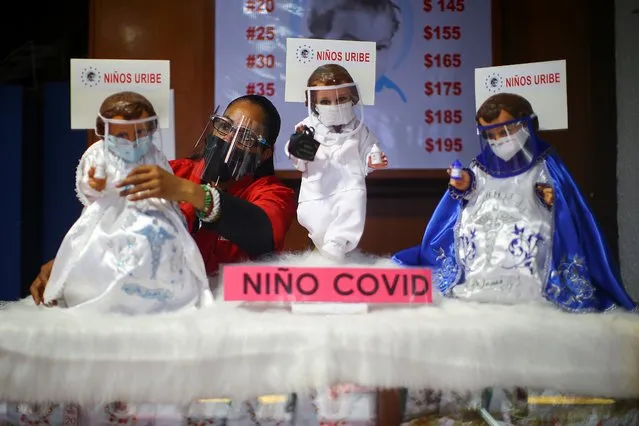 A saleswoman adjusts the suit of a dressed-up doll representing baby Jesus and wearing a face mask to promote the use of masks as a precautionary measure amid the coronavirus disease (COVID-19) outbreak before Christmas celebration, inside a store in Mexico City, Mexico, December 9, 2020. (Photo by Edgard Garrido/Reuters)