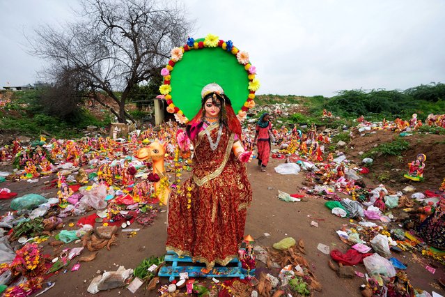 A woman searches for reusable material amid offerings and idols of Hindu goddess Dashama left by devotees on the banks of River Sabarmati after the end of the ten-days long Dashama festival in Ahmedabad, India, Wednesday, August 14, 2024. (Photo by Ajit Solanki/AP Photo)
