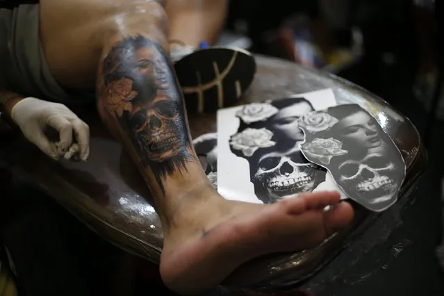 A man gets a tattoo of a woman's face and a skull on his leg during Rio Tattoo Week in Rio de Janeiro, Brazil, Friday, January 16, 2015. (Photo by Silvia Izquierdo/AP Photo)