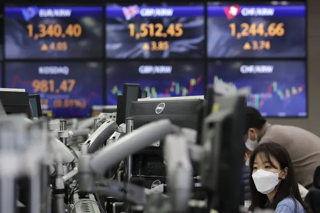 A currency trader watches computer monitors near the screens showing the foreign exchange rates at the foreign exchange dealing room in Seoul, South Korea, Friday, January 22, 2021. Asian stock markets retreated Friday after a resurgence of coronavirus infections in China and a rise in cases in Southeast Asia. (Photo by Lee Jin-man/AP Photo)