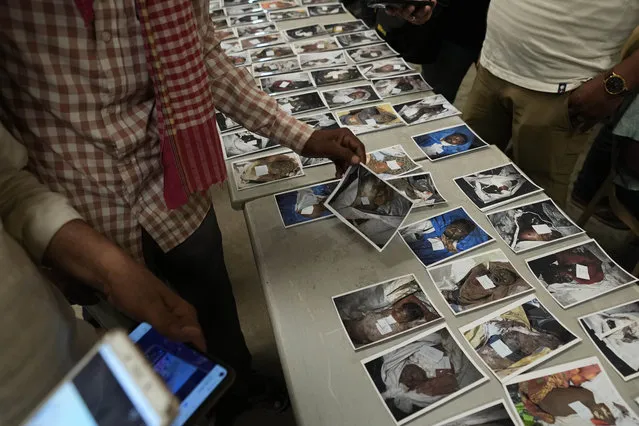 Relatives look at the photographs of unidentified bodies of passengers displayed for identification, in Balasore district, in the eastern Indian state of Orissa, Sunday, June 4, 2023. (Photo by Rafiq Maqbool/AP Photo)