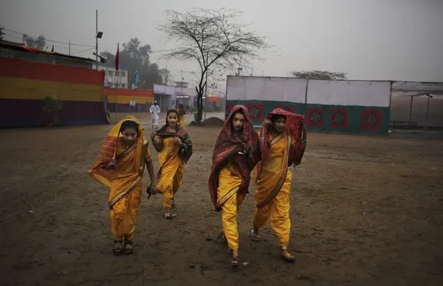 Artists from the Indian state of Maharashtra cover themselves from rain as they walk toward the venue of a media preview displaying a glimpse of culture of different parts of India, in New Delhi, India, Thursday, January 22, 2015. The tableaux will be part of the Indian Republic Day parade on Jan. 26. (Photo by Altaf Qadri/AP Photo)