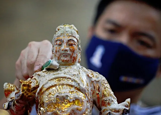 A man wearing a protective face mask washes a religious statue ahead of the Lunar New Year celebration at a temple in Jakarta, Indonesia, February 4, 2021. (Photo by Ajeng Dinar Ulfiana/Reuters)