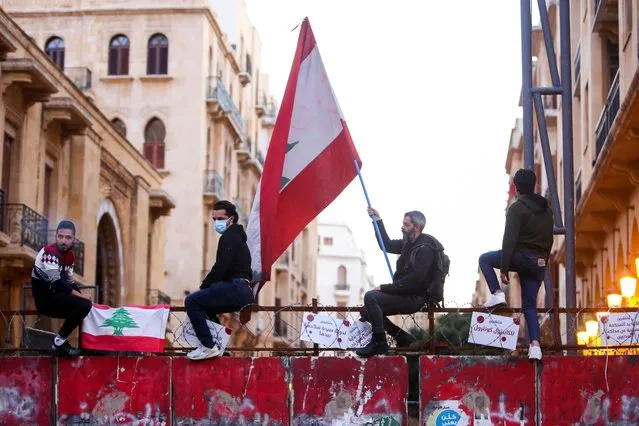 A demonstrator holds a Lebanese flag during a protest against the fall in Lebanese pound currency and mounting economic hardships, in Beirut, Lebanon on March 12, 2021. (Photo by Aziz Taher/Reuters)