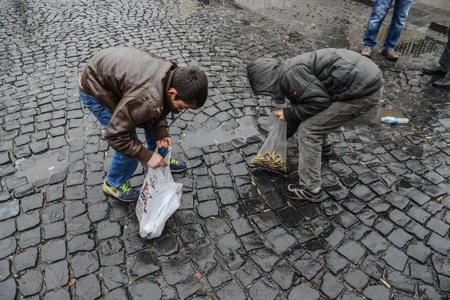 Children collect bullet shells off the streets of Sur district, on December 30, 2015 in the mainly Kurdish city of Diyarbakir, after a curfew was partially lifted. Tensions are running high throughout Turkey's restive southeast, as security forces have been imposing curfews in several towns in a bid to root out Kurdistan Workers' Party (PKK) rebels from urban centres. (Photo by Ilyas Akengin/AFP Photo)