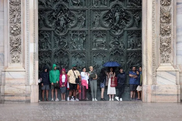 Tourists take shelter under the Duomo Cathedral as heavy rain hits Milan, Italy on July 6, 2023. (Photo by Claudia Greco/Reuters)
