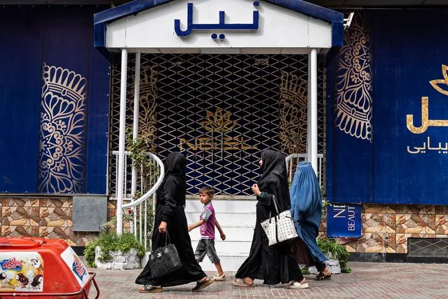 Afghan women walks past a closed beauty parlour in Kabul on July 25, 2023. Afghanistan's Taliban authorities have ordered beauty parlours across the country to shut within a month, the vice ministry confirmed the latest curb to squeeze women out of public life. (Photo by Wakil Kohsar/AFP Photo)