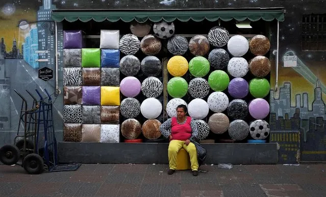 A woman sits in front of a shop selling stools after buying one in the Bras neighborhood of Sao Paulo August 9, 2013. (Photo by Nacho Doce/Reuters)