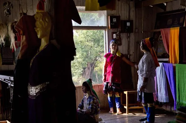 An ethnic Kayan-Padaung woman in traditional attire weaves at a souvenir shop as others watch in Ywama village, Inle Lake, northeastern Shan state, Myanmar, Monday, February 16, 2015. (Photo by Gemunu Amarasinghe/AP Photo)