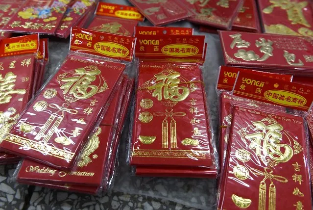 This photo taken on February 17, 2015 shows red “hongbao” packets for sale in a pedestrian underpass in Beijing. In China, the tradition of giving “hongbao”, or red envelopes, to celebrate the Lunar New Year is enjoying a resurgence in popularity online – a golden opportunity for Internet giants Tencent and Alibaba as they battle for the lucrative online payment market. (Photo by Greg Baker/AFP Photo)