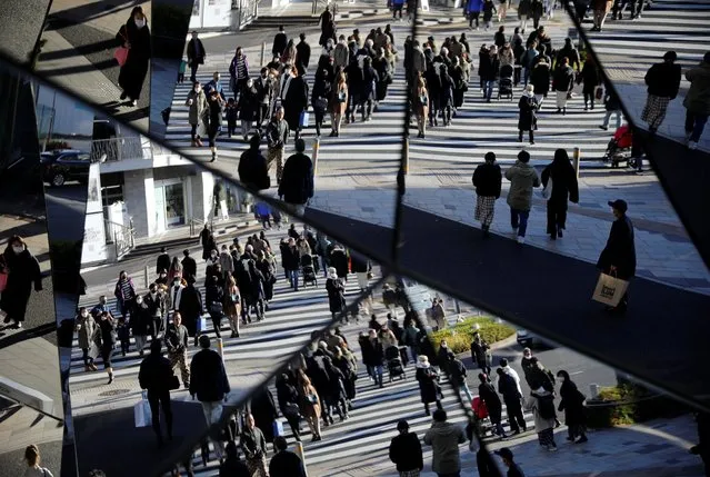 Year-end shoppers wearing protective face masks are reflected on mirrors at a shopping and amusement district, amid the coronavirus disease (COVID-19) outbreak, in Tokyo, Japan on December 31, 2020. (Photo by Issei Kato/Reuters)