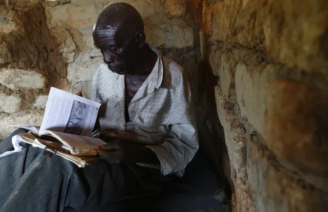 HIV-positive 71-year-old Sylverio Hachiploa reads in his thatched hut during a visit by a home-based care team in the village of Nedwmba, south of the Chikuni Mission in the south of Zambia February 23, 2015. (Photo by Darrin Zammit Lupi/Reuters)