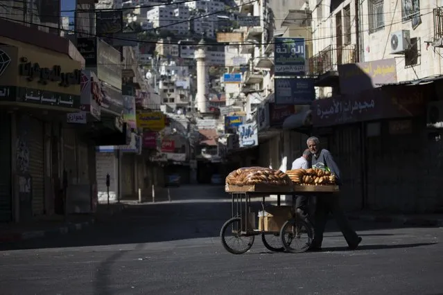 A Palestinian vendor pushes a cart loaded with bread during a general strike, in the West Bank city of Nablus, Tuesday, May 18, 2021. Palestinian leaders are calling for a general strike in Gaza, the West Bank and within Israel to protest against Israel's air strikes on Gaza and the violent confrontations between Israeli security forces and Palestinians in Jerusalem. (Photo by Majdi Mohammed/AP Photo)