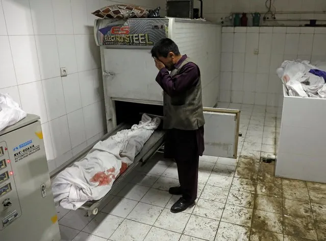 An Afghan man cries next to his daughter's body after a blast, at a hospital in Kabul, Afghanistan on May 8, 2021. (Photo by Reuters/Stringer)