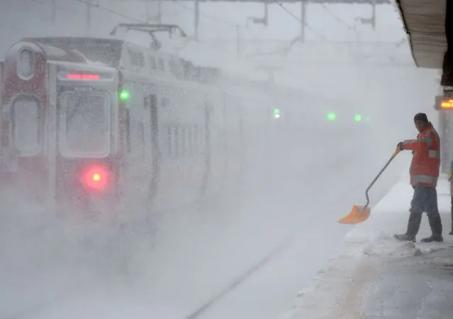 A worker cleans snow off the platform at the Metro North Train station in Greenwich, Connecticut on January 23, 2016. A deadly blizzard with bone-chilling winds and potentially record-breaking snowfall slammed the eastern US on January 23, as officials urged millions in the storm's path to seek shelter – warning the worst is yet to come. US news reports said at least eight people had died by late Friday from causes related to the monster snowstorm, which is expected to last until early Sunday. (Photo by Timothy A. Clary/AFP Photo)