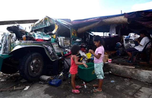 Children play beside a damaged jeepney converted into a living quarter in an area devastated by Typhoon Haiyan on November 11, 2013 in Leyte, Philippines. (Photo by Dondi Tawatao/Getty Images)