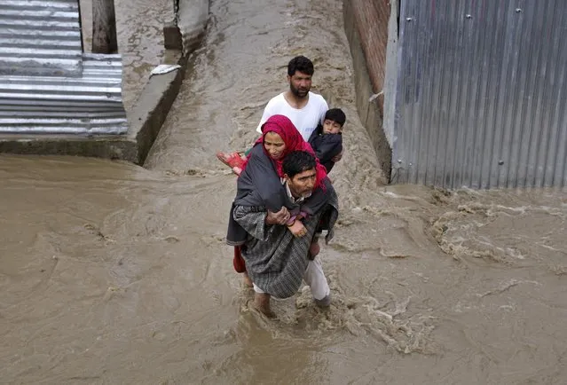 Kashmiri men assist a woman and a child to evacuate from a flooded area in Srinagar, Indian-controlled Kashmir, Monday, March 30, 2015. Authorities in Kashmir issued alerts Monday and asked people to move to higher ground after heavy rain flooded several parts of the Himalayan region. (Photo by Mukhtar Khan/AP Photo)