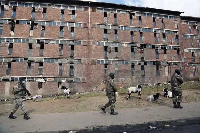 South African Defence Force soldiers on patrol alongside the male single s*x hostels in Alexandra Township, north of Johannesburg, Thursday, July 15 2021. The army has begun deploying 25,000 troops to assist police in quelling the weeklong riots and violence sparked by the imprisonment of former President Jacob Zuma. (Photo by AP Photo/Stringer)