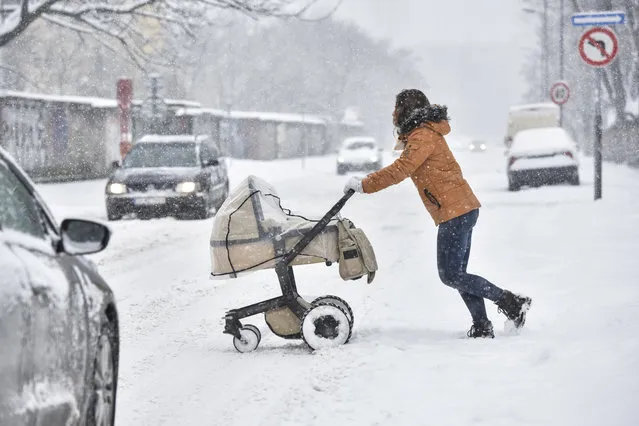 A woman pushes a pram across the street during heavy snowfall in Bratislava, Slovakia, Tuesday, January 8, 2019. Cold weather has engulfed many parts of Europe Tuesday. (Photo by Pavol Zachar/TASR via AP Photo)