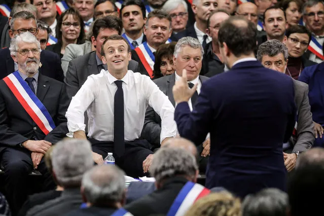 French President Emmanuel Macron smiles as he listens to French Junior Minister to the Minister of Territorial Cohesion and Relations with Territorial Communities, in charge of territorial communities Sebastien Lecornu during a meeting attended by some 600 mayors of Occitania to relay their constituent's grievances on January 18, 2019, in Souillac, southern France. (Photo by Ludovic Marin/Pool via Reuters)
