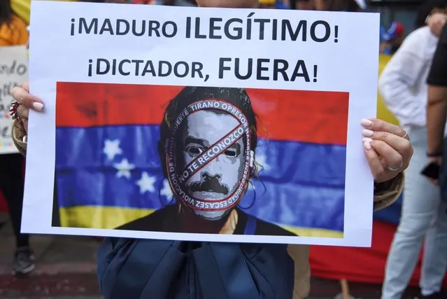 A sign reading “Maduro, illegitimate, dictator get out!” is held in a protest by Venezuelans outside their embassy in Guatemala City in support of opposition leader Juan Guaido's self-proclamation as acting president of Venezuela, on January 23, 2019. Venezuelan opposition leader Juan Guaido declared himself interim president Wednesday, while hundreds of thousands of Venezuelans poured onto the streets to demand an end to the government of Nicolas Maduro. (Photo by Orlando Estrada/AFP Photo)