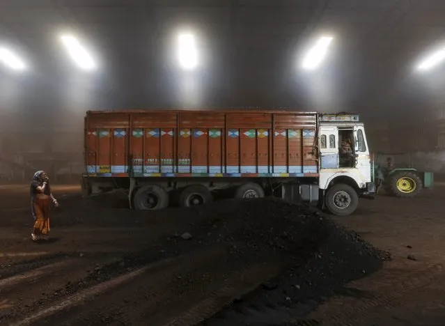 A worker speaks with the driver after unloading coal from a supply truck at a yard on the outskirts of the western Indian city of Ahmedabad April 15, 2015. (Photo by Amit Dave/Reuters)