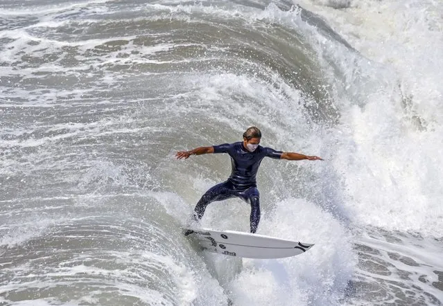 A surfer takes to the waves, north of the pier in Huntington Beach, Calif, Thursday, August 19, 2021. (Photo by Jeff Gritchen/The Orange County Register via AP Photo)