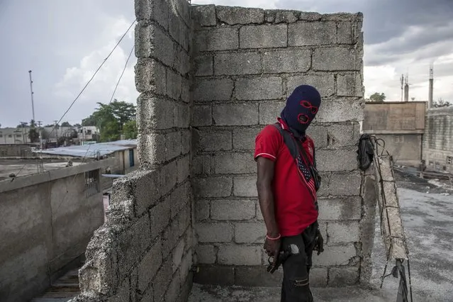 A gang member, wearing a balaclava and holding a gun, poses for a photo in the Portail Leogane neighborhood of Port-au-Prince, Haiti, Thursday, September 16, 2021. There could be as many as 100 gangs in Port-au-Prince; no one has an exact count and allegiances often are violently fluid. (Photo by Rodrigo Abd/AP Photo)