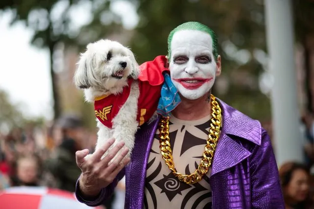 A man dressed up as the Joker holds a dog during the annual Tompkins Square Halloween Dog Parade at East River Park Amphitheater in New York on October 23, 2021. (Photo by Kena Betancur/AFP Photo)