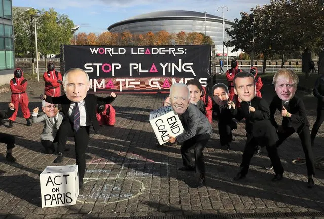 Climate campaigners wearing masks of world leaders enact a “Squid Game” themed protest stunt with a campaigner wearing a mask of Russian President Vladimir Putin, front left, and another wearing a mask of U.S. President Joe Biden, center, on the fringes of the COP26 U.N. Climate Summit, in Glasgow, Scotland, Tuesday, November 2, 2021. The U.N. climate summit in Glasgow gathers leaders from around the world, in Scotland's biggest city, to lay out their vision for addressing the common challenge of global warming. (Photo by Scott Heppell/AP Photo)