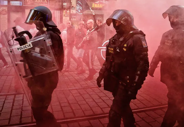Riot police officers walk along with marching right wing supporters following scuffles with left wing protesters in the city of Brno, Czech Republic, Wednesday, May 1, 2019. (Photo by Petr David Josek/AP Photo)