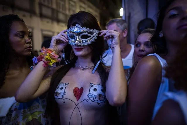 Topless dancers wait for a moment during a street parade of Banda da Rua do Mercado in Rio de Janeiro, Brazil, on Februrary 27, 2014. Rio's carnival will start officially from tomorrow for 5 days and have around 470 groups on streets. Samba school parades will have a peak at Sambodromo on March 2 and 3, 2014. (Photo by Yasuyoshi Chiba/AFP Photo)