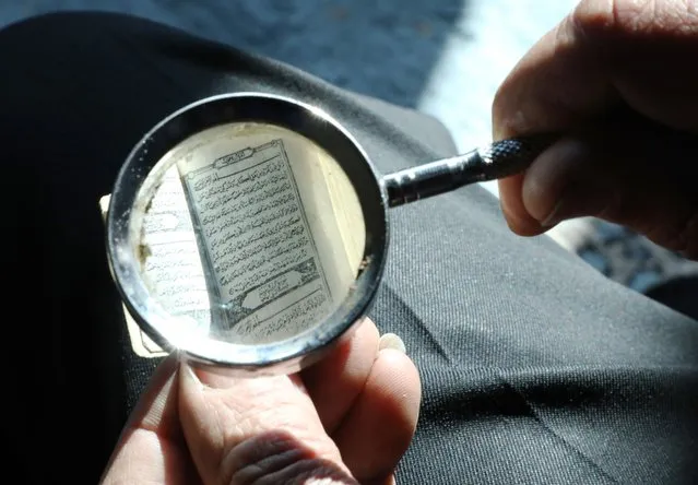Jordanian Ibrahim Ahmed Nevvar reads the smallest copy of the Quran, which attracts the attention of antique, cultural heritage and collection enthusiasts, with a magnifying glass at the Permanent Folk Heritage Museum, which he founded in As-Salt, Jordan on January 24, 2023. 1.50 centimeters wide and 2.5 centimeters long, with a green cover, the Quran can only be read with a magnifying glass, as the texts are very small. (Photo by Ahmed Shoura/Anadolu Agency via Getty Images)