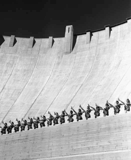 Top of Hoover Dam towers almost 600 feet above as the Rhythmettes, precision dancing group from nearby Las Vegas, Nevada High School; kick high during routine on what must be the world's largest stage June 8, 1957. (Photo by AP Photo)