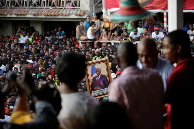 A man holds an image of Haitian President Jovenel Moise as Moise gives a speech during the parade of the Carnival in Jacmel, Haiti, February 19, 2017. (Photo by Andres Martinez Casares/Reuters)