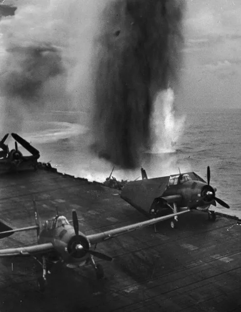 A bomb explodes in the water off the port side of an American aircraft carrier during the battle for Saipan, June 1944. The planes on the deck are Grumman TBF Avengers. (Photo by W. Eugene Smith/The LIFE Picture Collection/Getty Images)